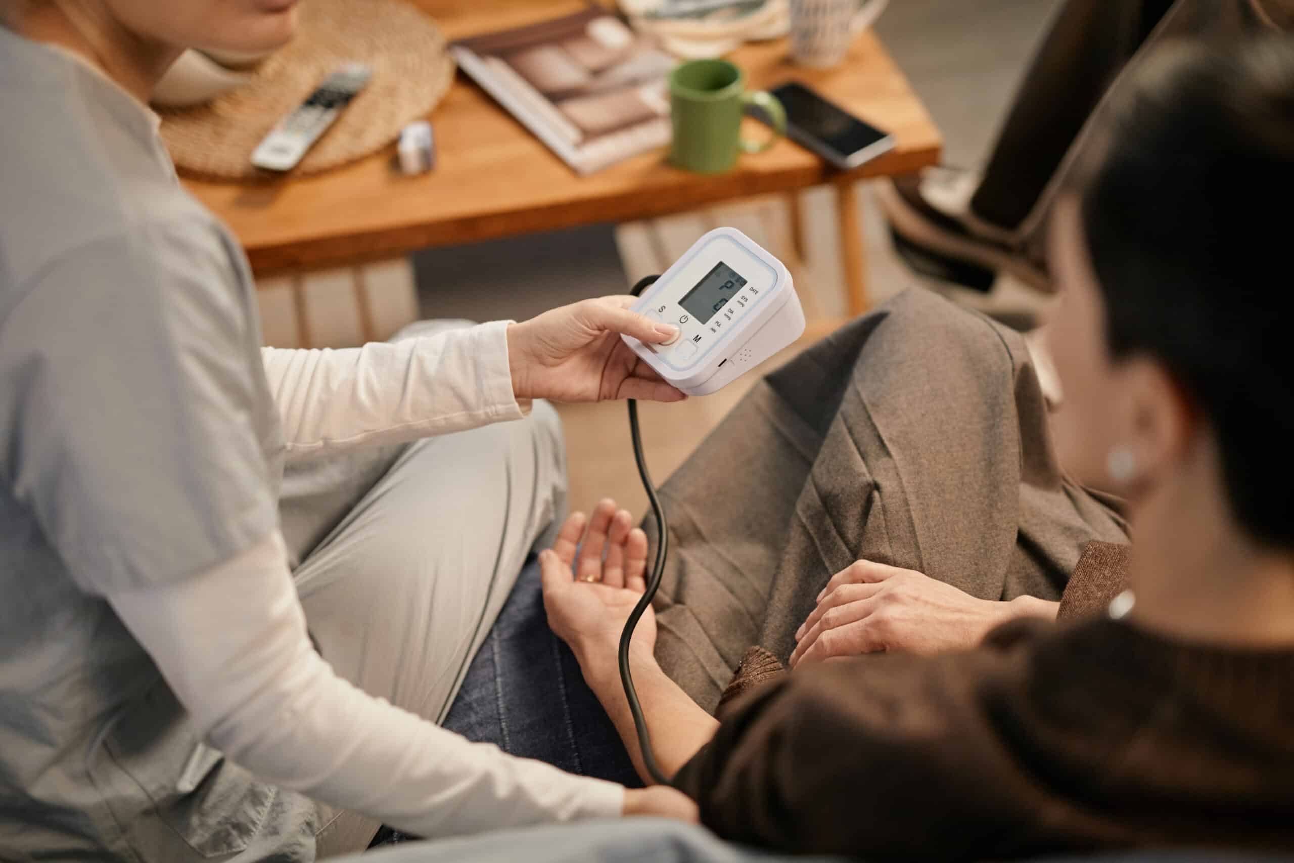 A clinical staff member taking a patient's blood pressure using a digital monitor during vital signs monitoring at an inpatient residential stabilization program in South Jersey, New Jersey